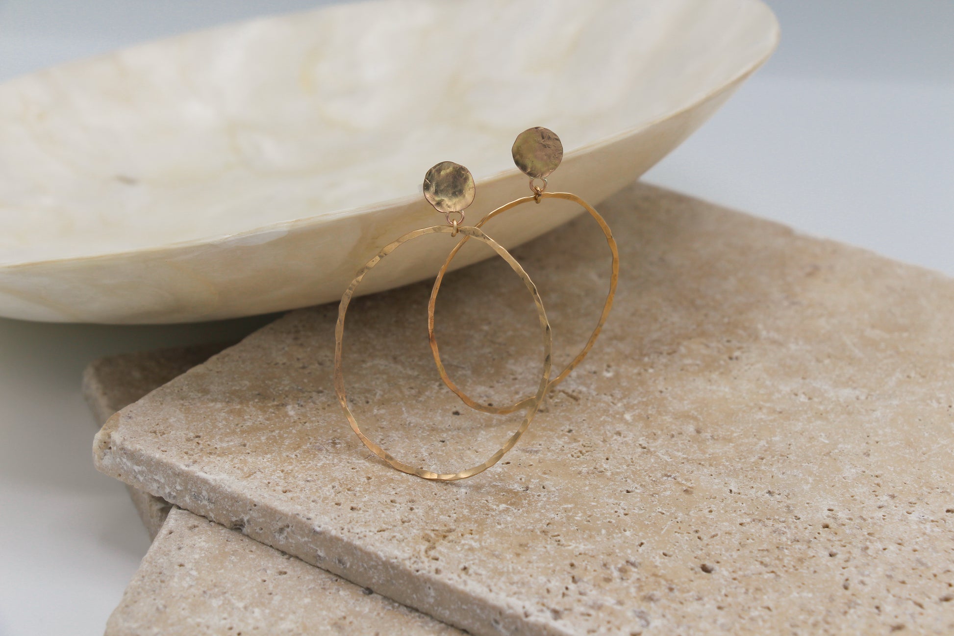Handmade geometric earrings with a circle stud and an attached wire oval all in a hammered finish.