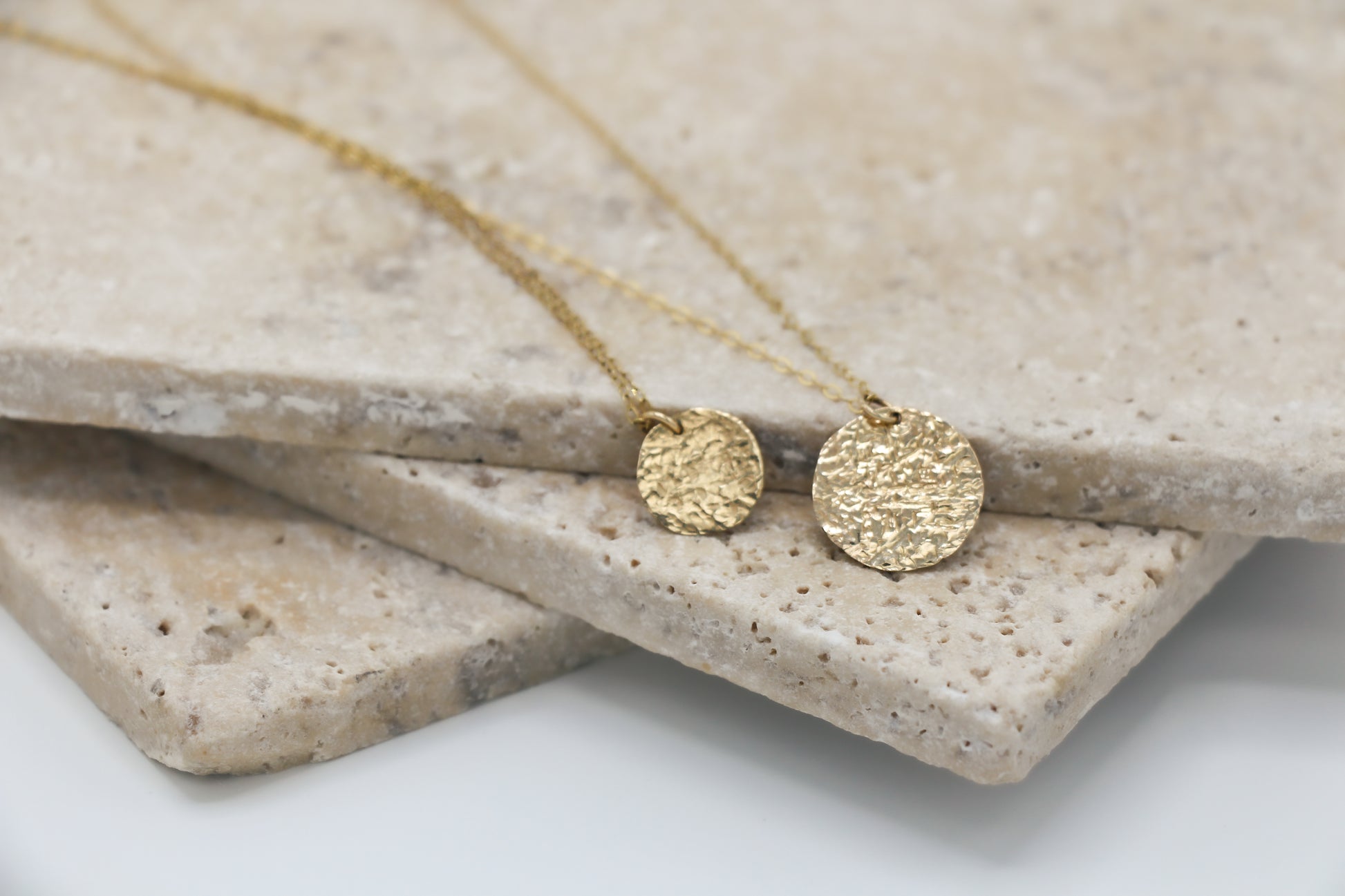 Gold necklace with round pendants on a stone surface