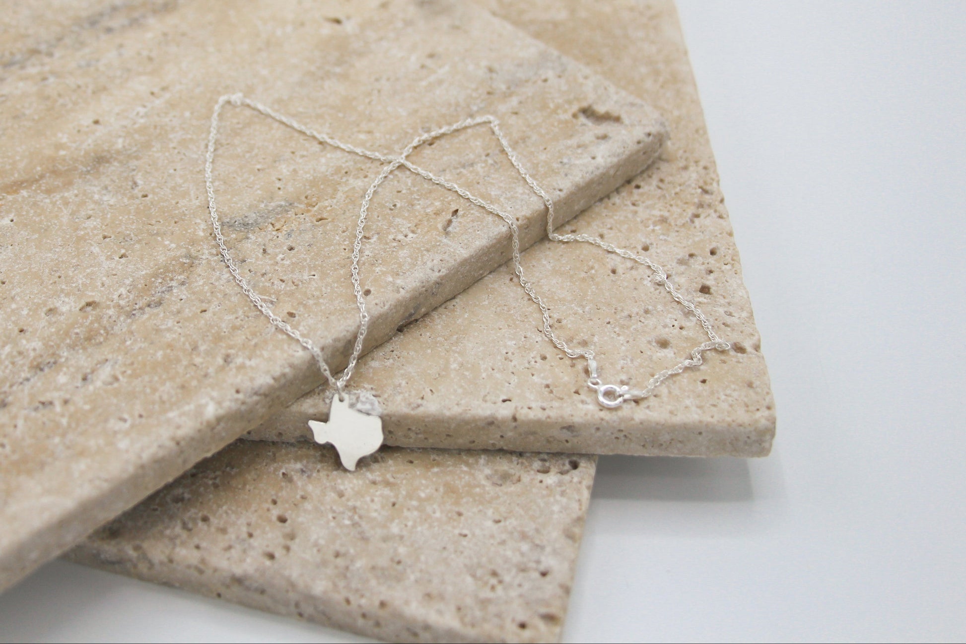 Texas state outline hand cut from sterling silver put on a dainty necklace chain