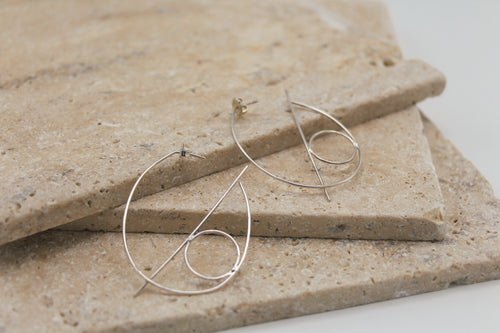 Oval shaped thin wire hoops with geometric shapes of one line and one circle to enhance the design 